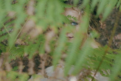 Close-up portrait of young woman seen through plant