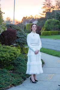 Portrait of smiling young woman standing on footpath