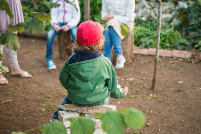 Rear view of boy sitting at yard