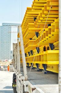 Rear view a large truck carrying heave yellow steel girders at a  construction site