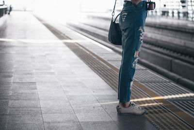Low section of person standing on railroad station platform