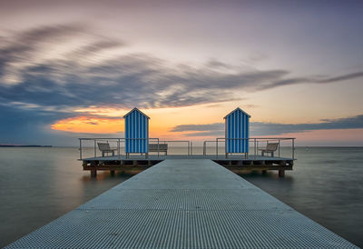 Pier on sea against cloudy sky during sunset