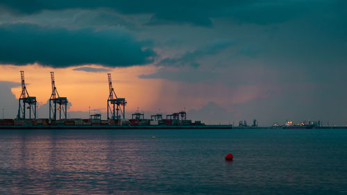 Commercial dock by sea against sky during sunset