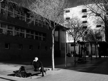 Man sitting on bench against building in city