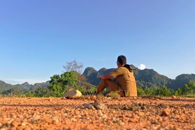 Man sitting on land against clear sky
