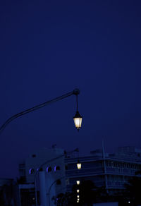 Illuminated street light against clear blue sky at night