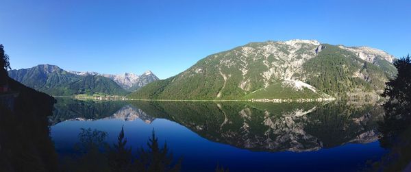 Scenic view of lake and mountains against clear blue sky