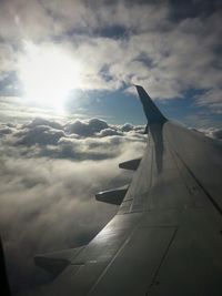 Cropped image of airplane wing against cloudy sky