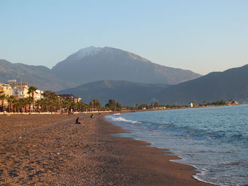 Scenic view of beach and mountains against clear sky