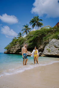 People on beach by palm trees against sky