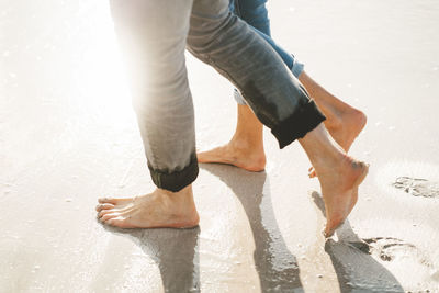 Mature man and woman walking barefoot on shore at beach