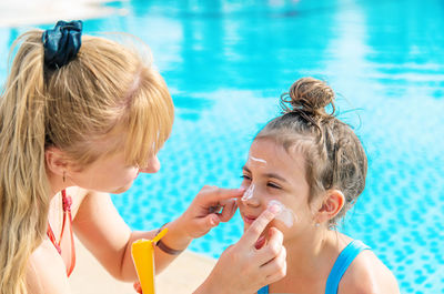 Mother applying suntan lotion on daughters face