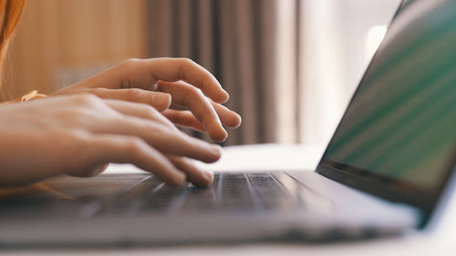 Cropped hands of woman using laptop