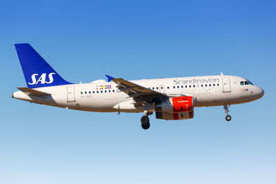 Low angle view of airplane flying against clear blue sky