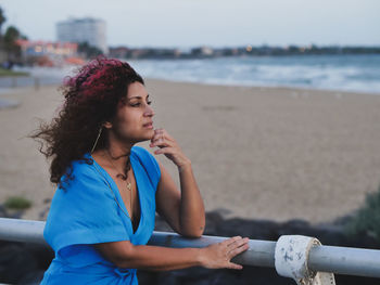 Young woman looking away while relaxing on beach