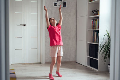 Child warms up before training at home. girl stands on tiptoes and pulls her hands up