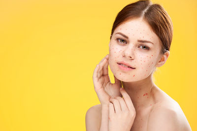 Portrait of young woman against yellow background