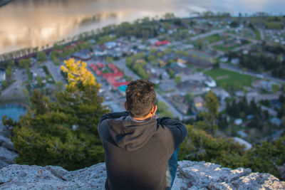 Rear view of man standing on rock against sky