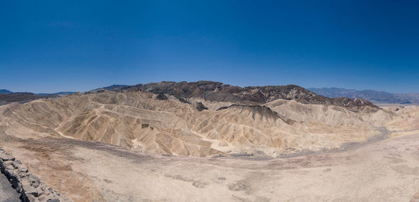 Scenic view of arid landscape against clear blue sky