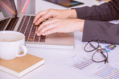 Close-up of man using laptop on table