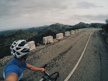 Road leading towards mountains against cloudy sky