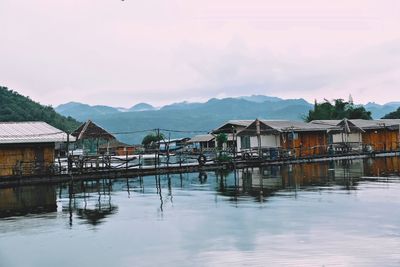 Houses by lake and mountains against sky