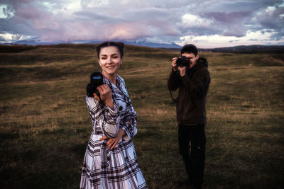 Young women standing on field against sky