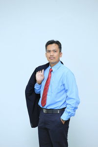 Portrait of a young man standing against clear sky