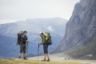 Rear view of men standing on mountain against sky