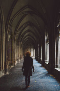Rear view of young woman standing at church corridor