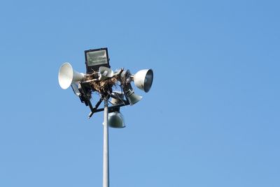 Low angle view of megaphones on pole against clear blue sky