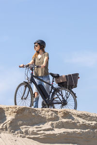 Man riding bicycle on land against sky