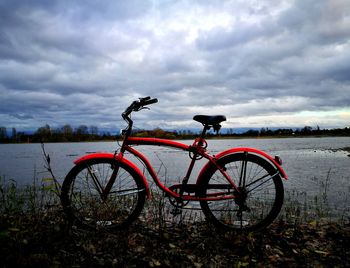 Bicycle by lake against sky