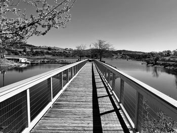 Footbridge over lake against clear sky