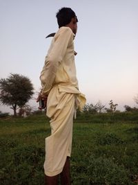 Full length of man standing on field against clear sky