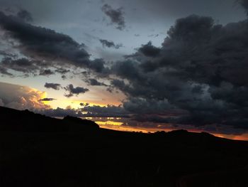 Scenic view of silhouette mountain against dramatic sky during sunset