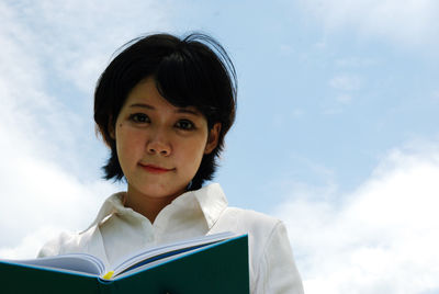 Low angle view of woman with diary against sky
