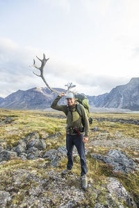 Backpacker holds up caribou antler to his head on remote baffin island