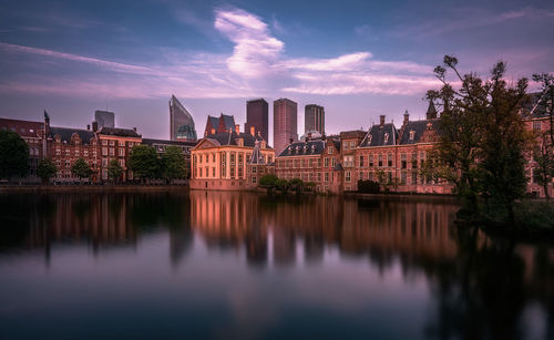 View of buildings by river against sky