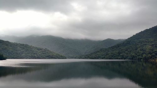 Scenic view of lake and mountains against cloudy sky