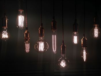 Various lit light bulbs hanging against sky at night