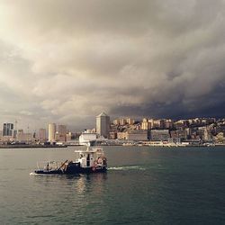 Boats in river against cloudy sky