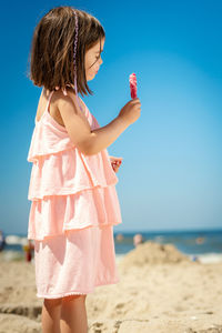 Cute girl looking away while eating ice cream at beach