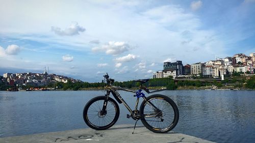 Bicycle by river against buildings in city