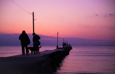 Silhouette people on pier against sky during sunset