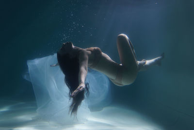 Woman with curtain swimming in pool