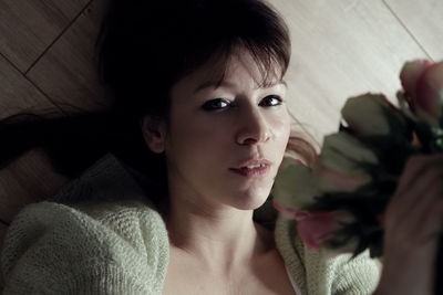 Close-up portrait of mid adult woman lying hardwood floor at home