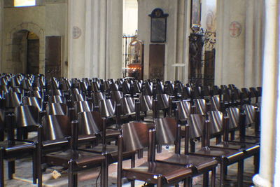 Empty chairs and tables in row against building
