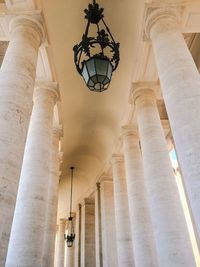 Low angle view of lighting equipment hanging from ceiling in historic building