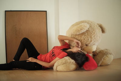 Woman lying on teddy bear at home